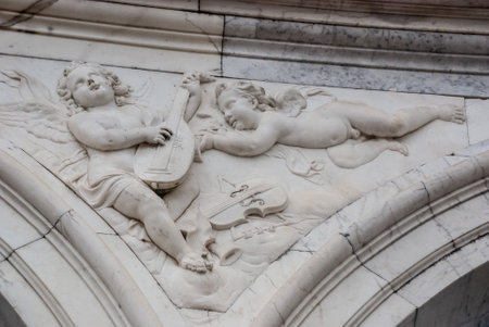 A closeup of sculptured statues of baby angels on the facade of a wall in Paris, Franceの写真素材