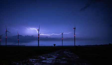 A beautiful night scenery view of a snowy road and Windmills under a lightning sky