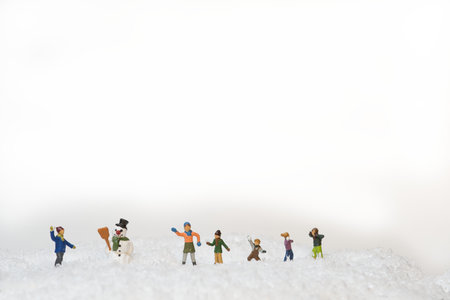 A group of miniature figures of kids throwing snowballs in snow around a snowmanの写真素材