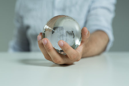 A 3D rendering of a man with a glass globe against a blurred backgroundの写真素材