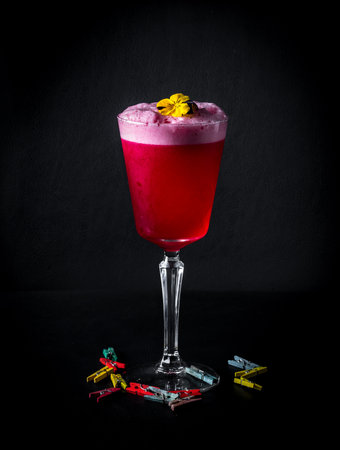 A vertical shot of a cocktail glass with flowers and little clothespins isolated on a black backgroundの写真素材