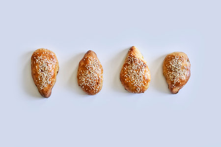 An overhead shot of homemade pies with sesame seeds on white backgroundの写真素材