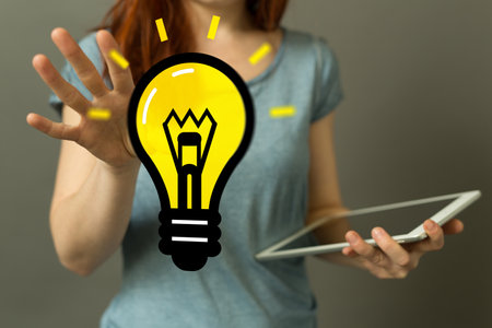 A 3D rendering light bulb icon floating on a woman's hand - new idea conceptの写真素材