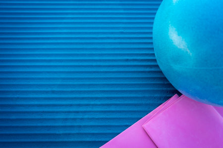 A closeup shot of a blue and pink yoga mat and an exercise ball with copy spaceの写真素材