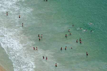 An aerial shot of a wavy and sandy beach of the sea with tourists, Portugalの写真素材