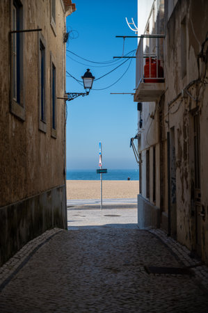 A vertical shot of an alley with a view of the sea in Nazare in Portugalの写真素材
