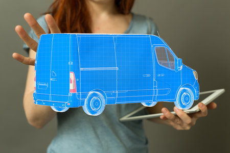 A woman touching the 3D rendering of a hologram wireframe van in a man's handsの写真素材
