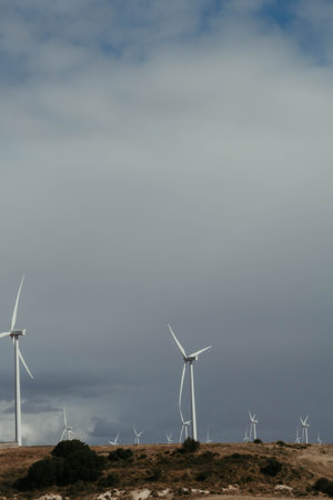 A vertical shot of wind turbines spinning on a valley