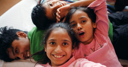 An overhead shot of four siblings lying on bed on a lazy day