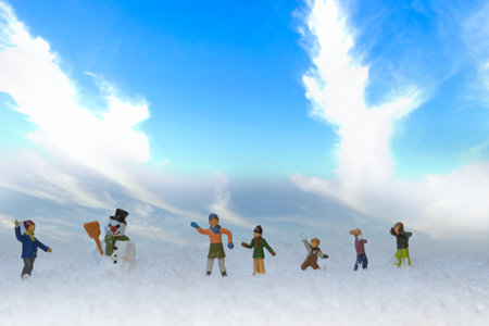 A group of miniature figures of kids throwing snowballs in snow around a snowmanの写真素材