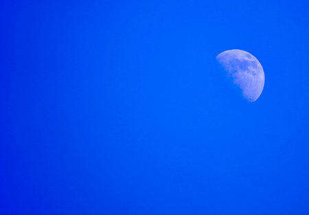 The waxing moon during the day. Moon surface with blue sky.の写真素材