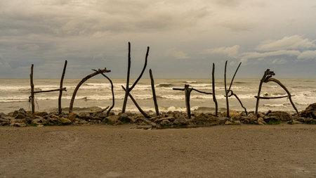A scenic view of the Hokitika Driftwood sign on the shores of New Zealandの写真素材