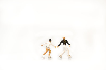 Two miniature figures of ice skaters on a white backgroundの写真素材