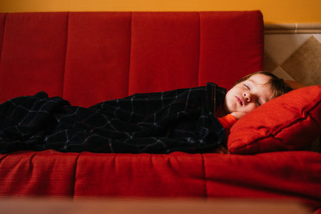 A young Caucasian kid sleeping on a red sofaの写真素材
