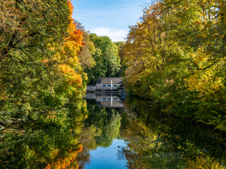 A small house surrounded with trees with colorful leaves and its beautiful reflection in the lake