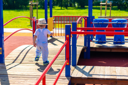 A closeup of a young boy walking on a wooden platform in a playground in the Rataje parkの写真素材
