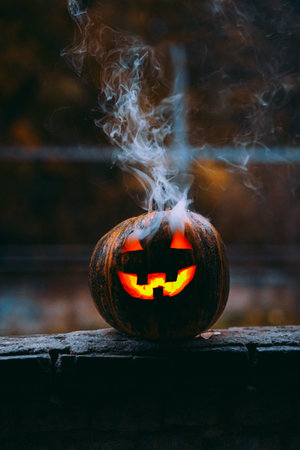 A vertical shot of an illuminated scary jack-o-lantern with smokeの写真素材