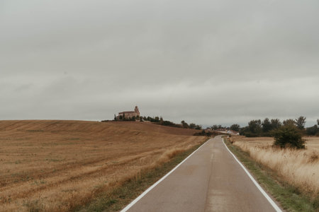 A road cutting through plains in Atapuerca, Burgos on a cloudy sky backgroundの写真素材