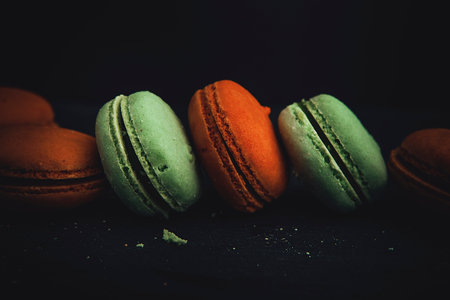 A close-up shot of colorful macaroons in the dark background
