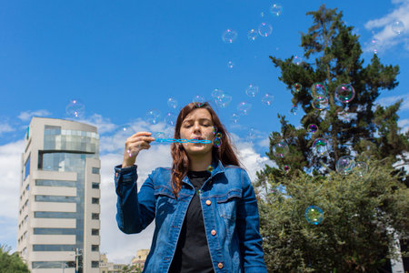 A beautiful shot of a girl with a bubble blower on a sunny day