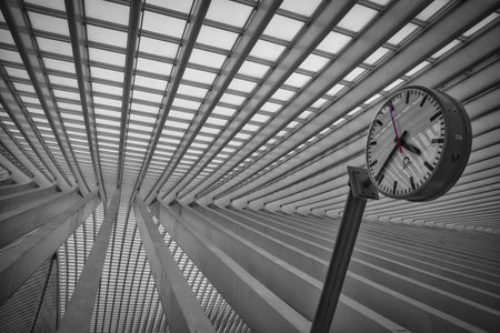 A grayscale shot of a clock near an architectural ceiling