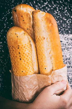 A closeup of french Baguettes bread in a paper bag in hands