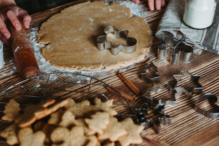 A top-view of a female baker's hands cutting ginger cookies for Christmas on a rustic wooden boardの写真素材