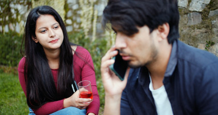 A shallow focus of a young adult Indian man talking on the phone during a party in a gardenの写真素材