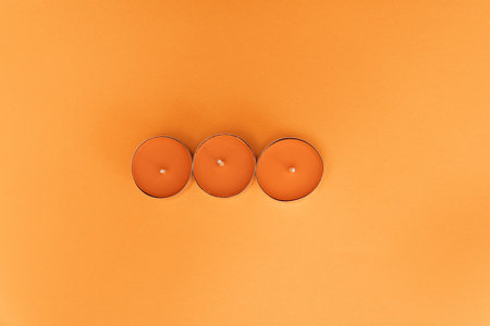 A closeup of decorative candles on an orange background