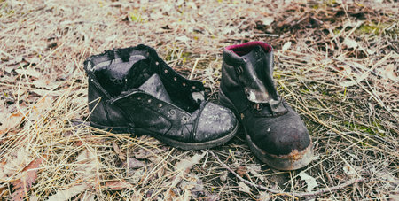 A high angle closeup of old worn dirty shoes on the ground