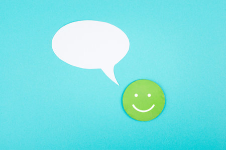 Smiling face with a speech bubble, blue colored background, copy space, rating, positive feedback,...