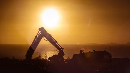 A silhouette of an excavator at sunset