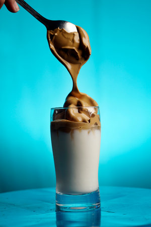 Dalgona Coffee Preparation, pouring the thick dark coffee froth into the glass of cold milkの写真素材