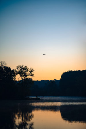 A vertical shot of a beautiful lake with the reflection of the sunset and trees