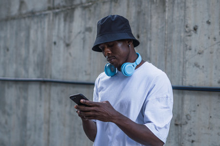 A shot of a man with white t shirt and a blue headset standing in the street and using phone, Spain