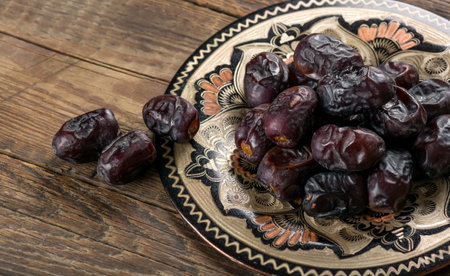 A closeup of the sweet dates in the plate on the wooden surfaceの写真素材