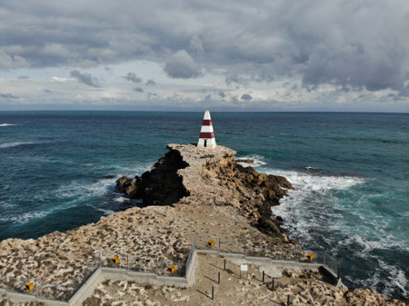 A narrow rocky walkway surrounded with foam sea wavesの写真素材