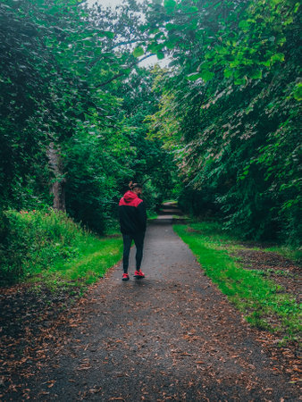 A young man walking along a path through the parkの写真素材