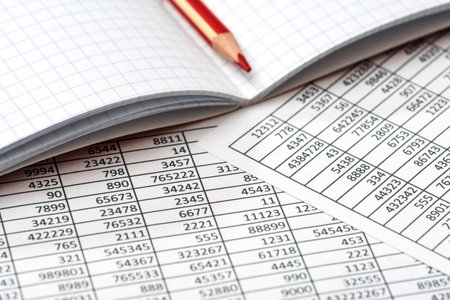 A closeup shot of a red pencil on a graphing notebook and documents for correction