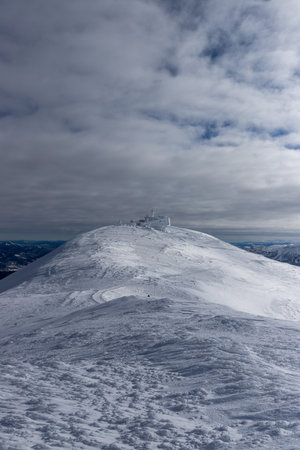 A vertical shot of pistes on hills covered in the snow under a cloudy skyの写真素材