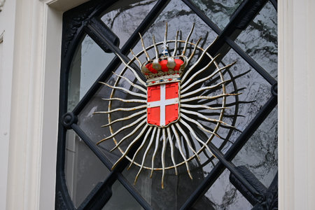 The swiss red and white metallic coat of arms on a glass doorの写真素材