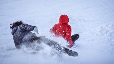 Two friends sliding with sleds on snow in winterの写真素材
