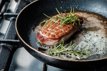 A closeup shot of delicious duck breast fillet frying in a pan