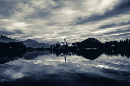 A breathtaking scene of a shiny cloudy sky and  mountains reflecting on Lake Bled, Slovenia