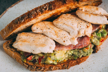 A closeup shot of a gourmet sandwich with chicken and guacamole on a plateの写真素材