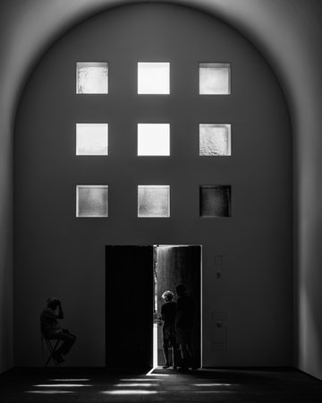 A grayscale shot of a couple exiting a door with an old man left behind