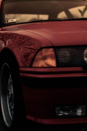 A vertical shot of a red car on the road outdoors