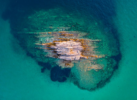 a Aerial top view of rock in the middle of a turquoise seaの写真素材