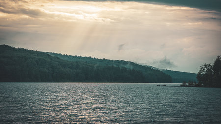 A landscape view of trees and lake on a misty day at sunsetの写真素材