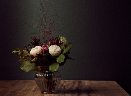 A closeup of an arrangement of beautiful flowers in a clear glass vase on a wooden tableの写真素材